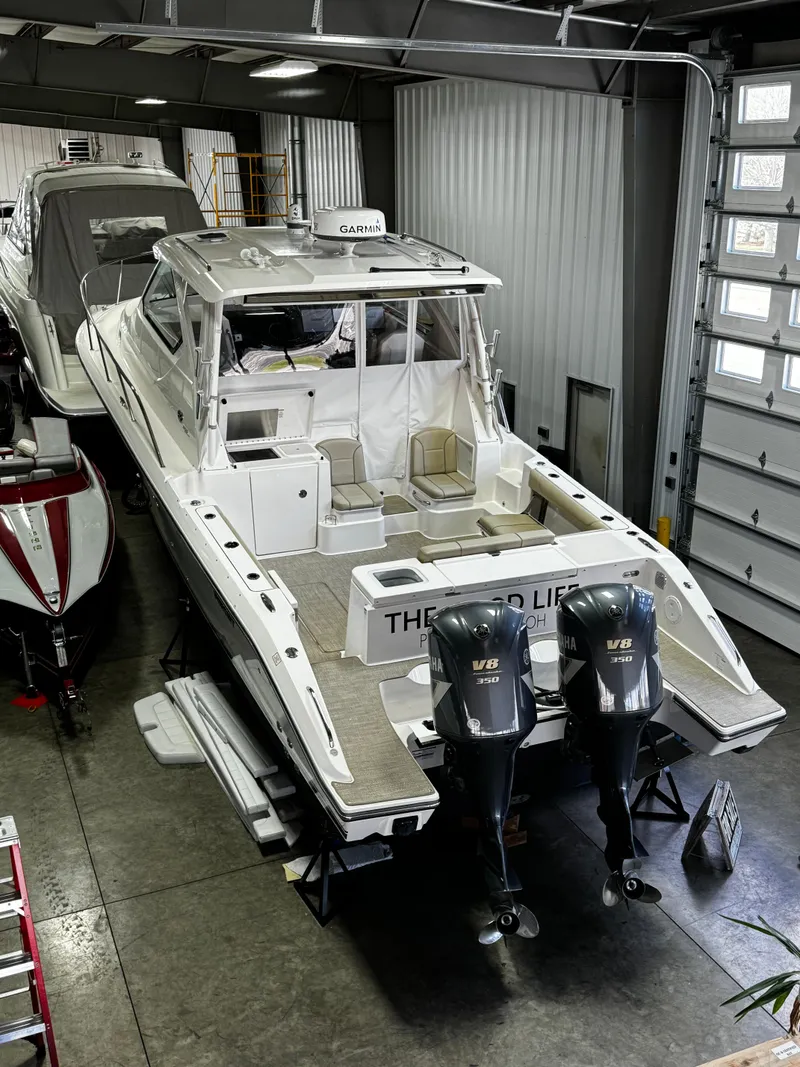 Slide: The Image of 2018 Pursuit OS 355 Offshore boat in a garage with twin outboard motors. - 49