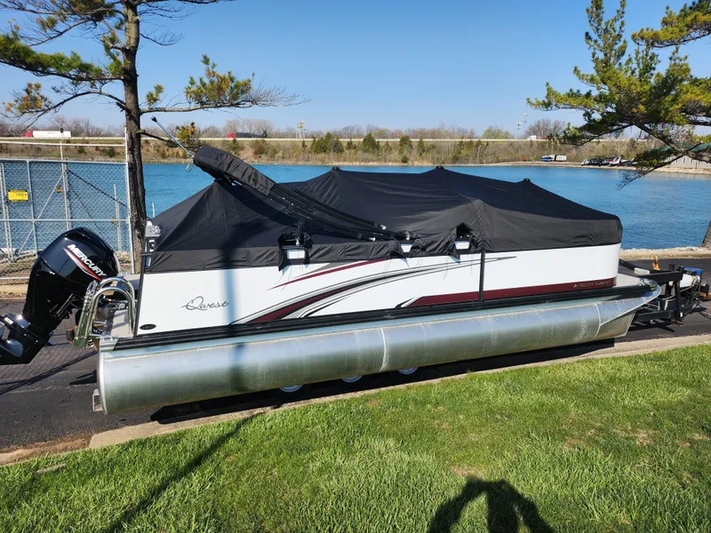 Slide: The Image of 2024 Qwest Angler Qwest XRE pontoon boat covered, parked by a lakeside. - 10
