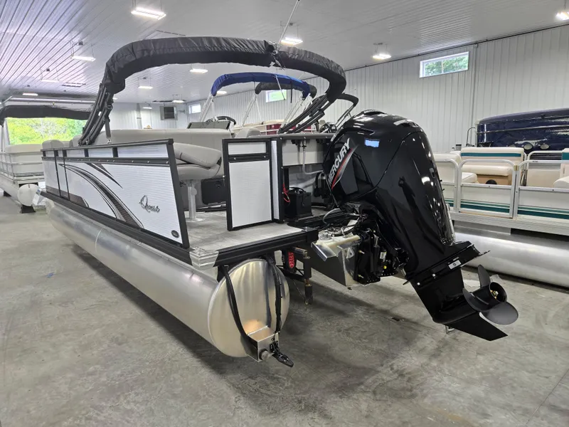 Slide: The Image of 2024 Qwest Angler Qwest XRE pontoon boat with Mercury outboard motor in showroom. - 2