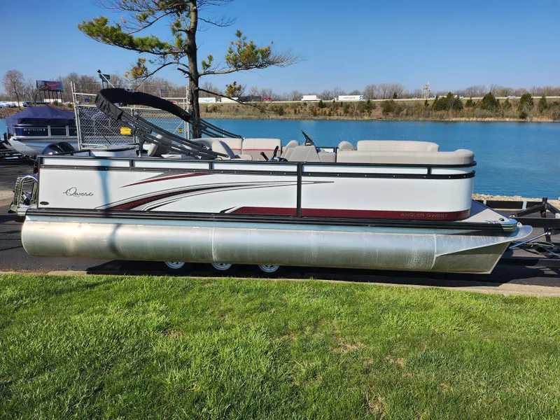 Slide: The Image of 2024 Qwest Angler Qwest XRE pontoon boat by a lake on a sunny day. - 9