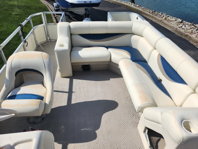 Slide: The Image of 2007 Odyssey Pontoons 222C interior with cream and blue seating, near water. - 14