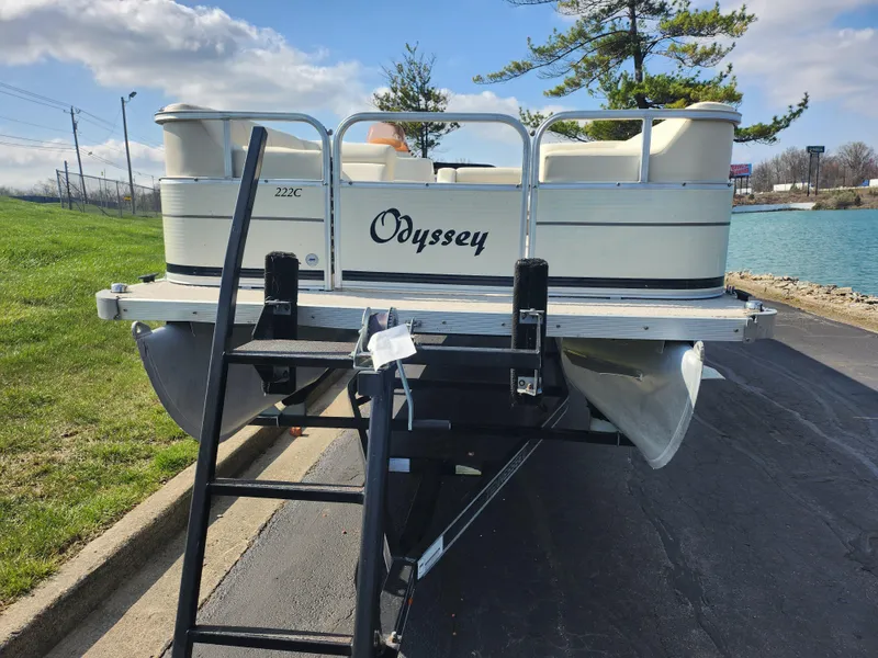 Slide: The Image of 2007 Odyssey Pontoons 222C on trailer, parked near a lake with a ladder attached. - 6