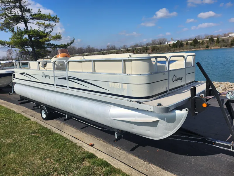 Slide: The Image of 2007 Odyssey Pontoons 222C on trailer by a lake, under a clear blue sky. - 8