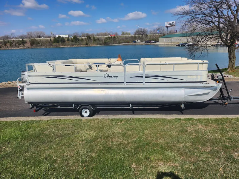 Slide: The Image of 2007 Odyssey Pontoons 222C on trailer by a lake, under a clear blue sky. - 9