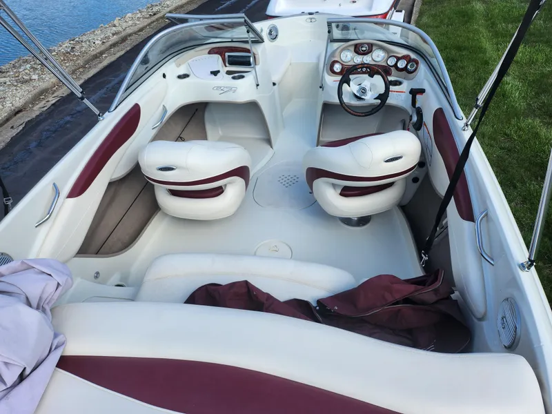 Slide: The Image of 2013 Tahoe Q7i boat interior with white and maroon seating, near water and grass. - 10