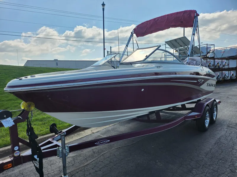 Slide: The Image of 2013 Tahoe Q7i boat with red canopy on trailer, parked outdoors. - 5