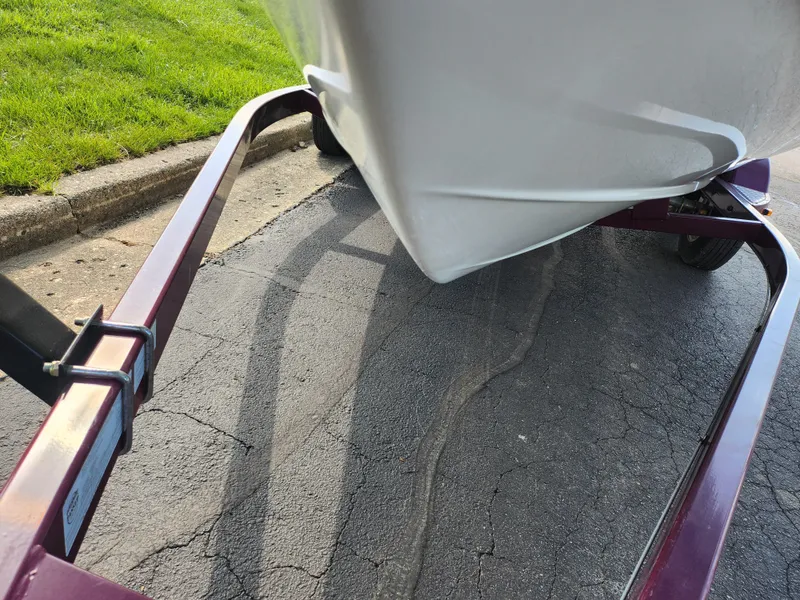 Slide: The Image of 2013 Tahoe Q7i boat on a trailer, parked on a paved surface near grass. - 7