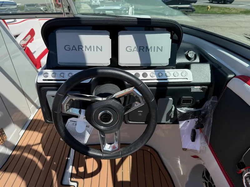 Slide: The Image of Steering wheel and Garmin displays on 2025 Crownline Eclipse E235 boat dashboard. - 12