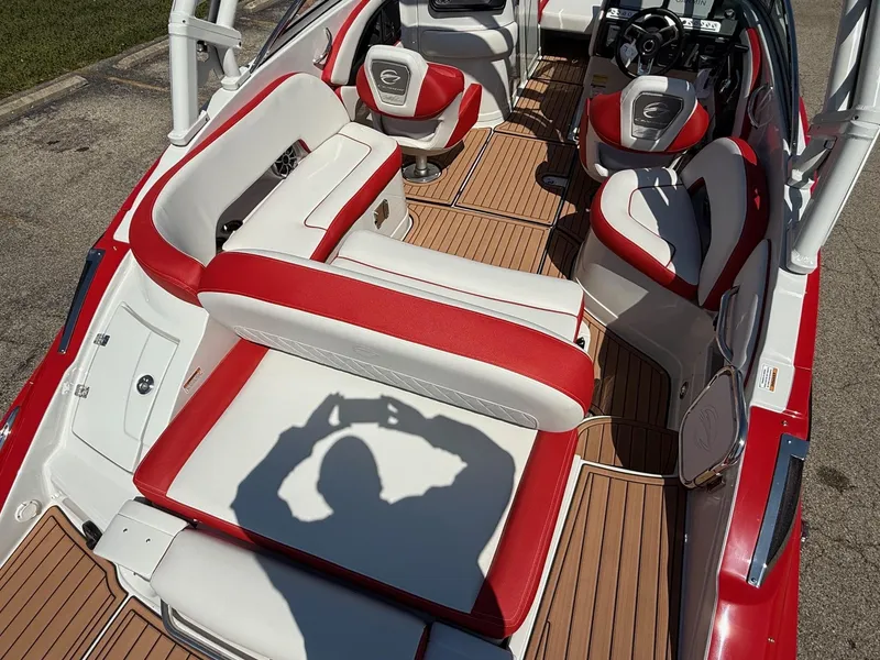 Slide: The Image of 2025 Crownline Eclipse E235 boat interior with red and white seating, wooden flooring, and steering console. - 6