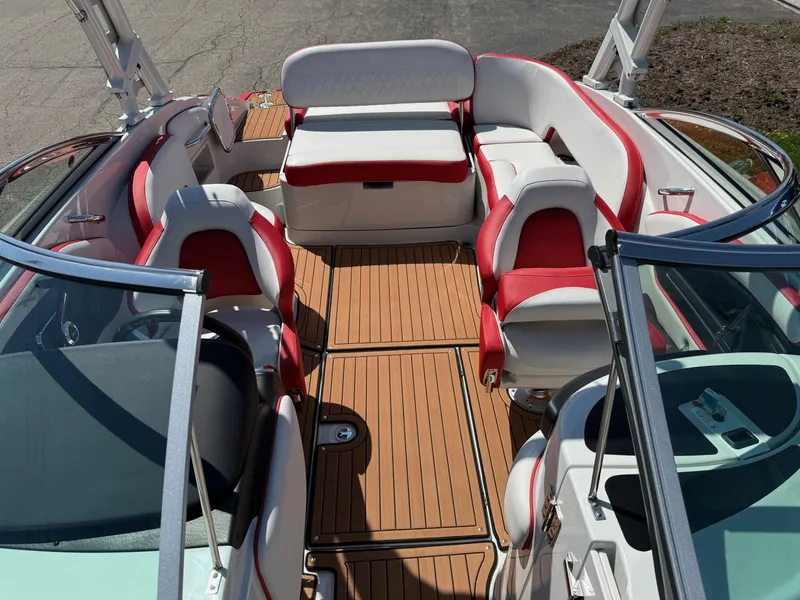Slide: The Image of 2025 Crownline Eclipse E235 boat interior with red and white seating and teak-style flooring. - 7