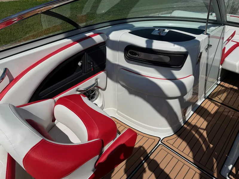 Slide: The Image of 2025 Crownline Eclipse E235 boat interior with red and white seating, modern dashboard, and wood-style flooring. - 9