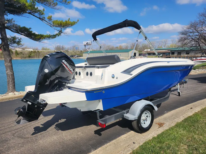 Slide: The Image of 2021 Bayliner DX 2000 boat on trailer by a lake, under a clear blue sky. - 1