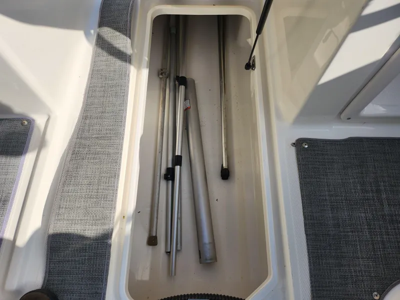 Slide: The Image of Storage compartment on a 2021 Bayliner DX 2000 boat with metal poles inside. - 16