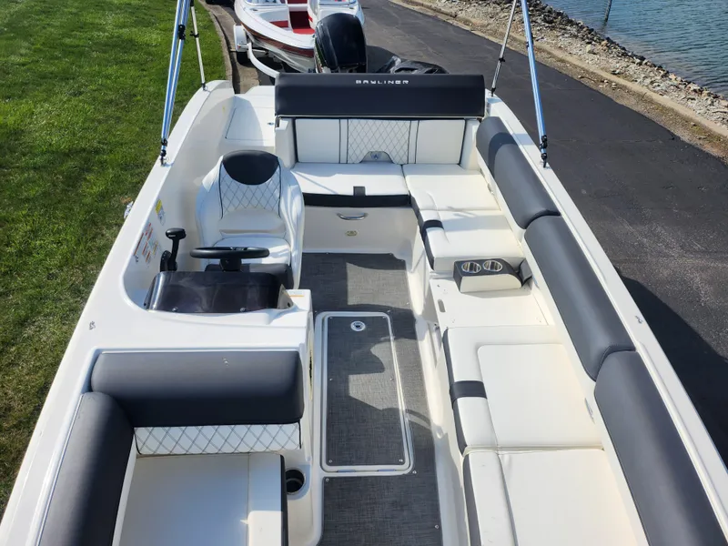 Slide: The Image of 2021 Bayliner DX 2000 boat interior with seating and steering, docked by a lakeside. - 21
