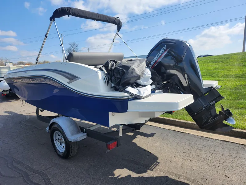 Slide: The Image of 2021 Bayliner DX 2000 boat with Mercury outboard motor on trailer, parked outdoors. - 3