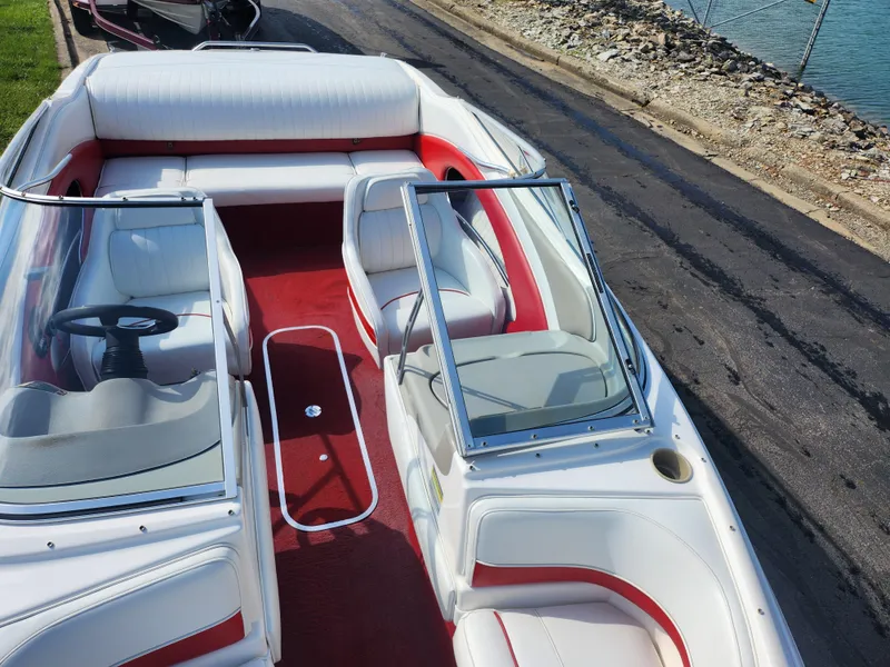 Slide: The Image of 1997 Bayliner 2050 Capri SS boat with red and white interior, docked by the water. - 18