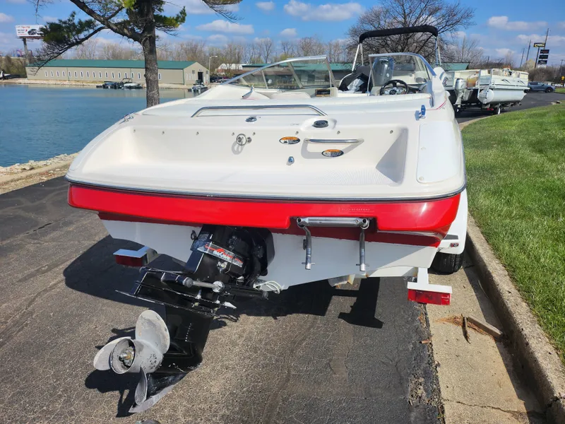 Slide: The Image of 1997 Bayliner 2050 Capri SS boat, rear view, parked near a lake on a sunny day. - 2