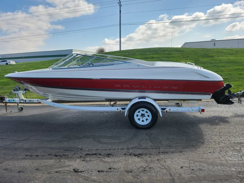 Slide: The Image of 1997 Bayliner 2050 Capri SS boat on trailer, red and white design, parked outdoors. - 4