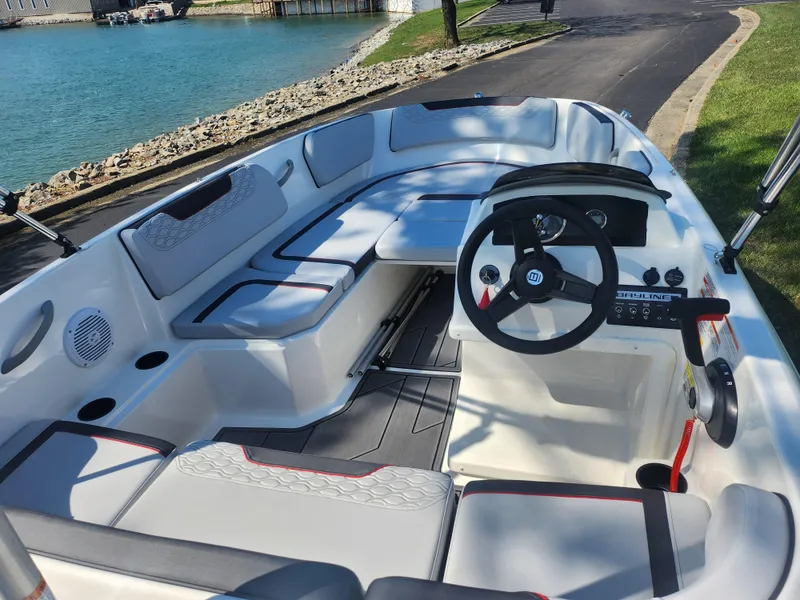 Slide: The Image of 2023 Bayliner Element M15 boat interior with steering wheel and seating, docked by a lake. - 10