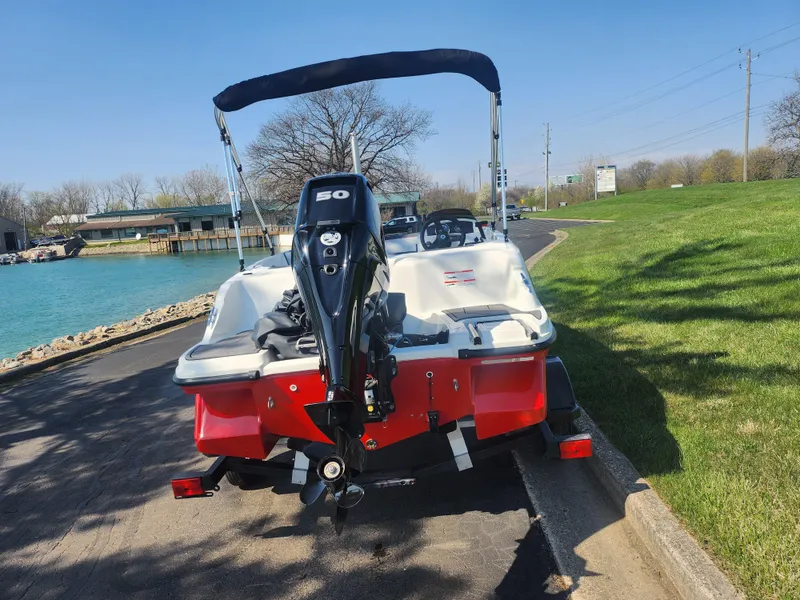 Slide: The Image of 2023 Bayliner Element M15 boat with outboard motor, parked near a scenic waterfront. - 2