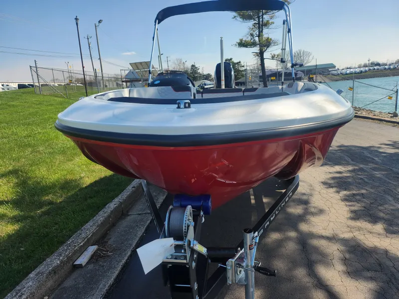 Slide: The Image of 2023 Bayliner Element M15 boat on trailer, red hull, parked near water. - 6