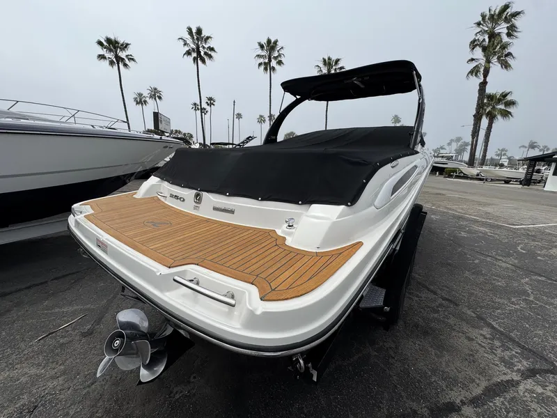 Slide: The Image of 2012 Sea Ray 250 SLX boat with teak deck, parked near palm trees. - 10