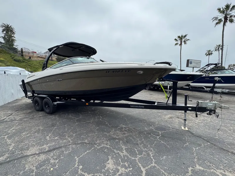 Slide: The Image of 2012 Sea Ray 250 SLX boat on trailer, parked outdoors with palm trees in background. - 2