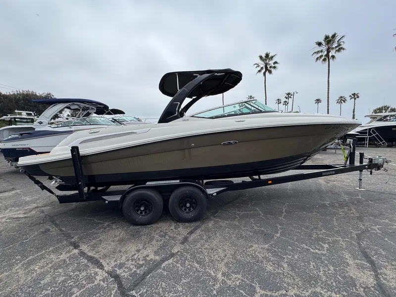 Slide: The Image of 2012 Sea Ray 250 SLX boat on trailer, parked outdoors with palm trees in background. - 4