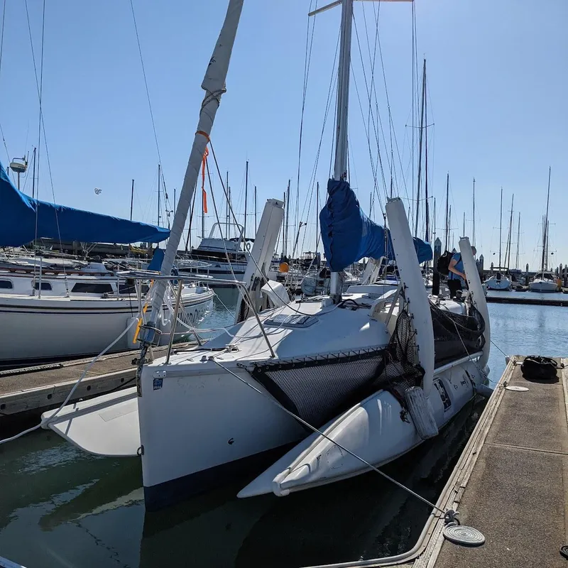 Slide: The Image of 1996 Corsair F-31 sailboat docked in a sunny marina, featuring blue sails and a spacious deck. - 11