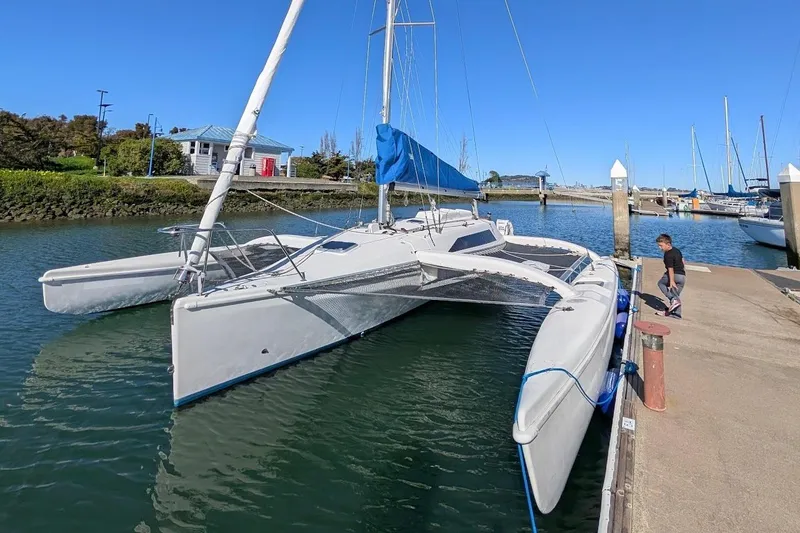 Slide: The Image of 1996 Corsair F-31 trimaran docked in a marina with blue sail and clear sky. - 12