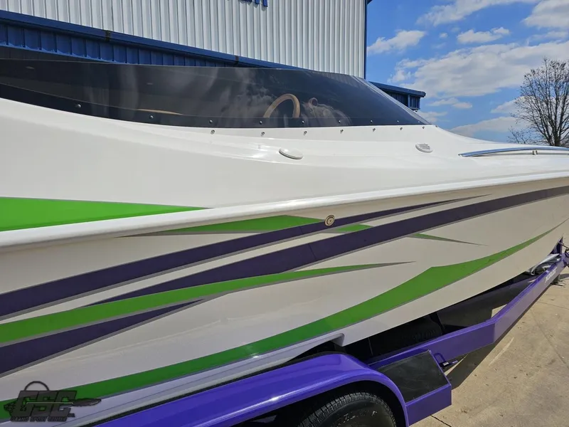 Slide: The Image of 2007 Nordic 28 Heat MCOB boat with green and purple accents on a trailer. - 14