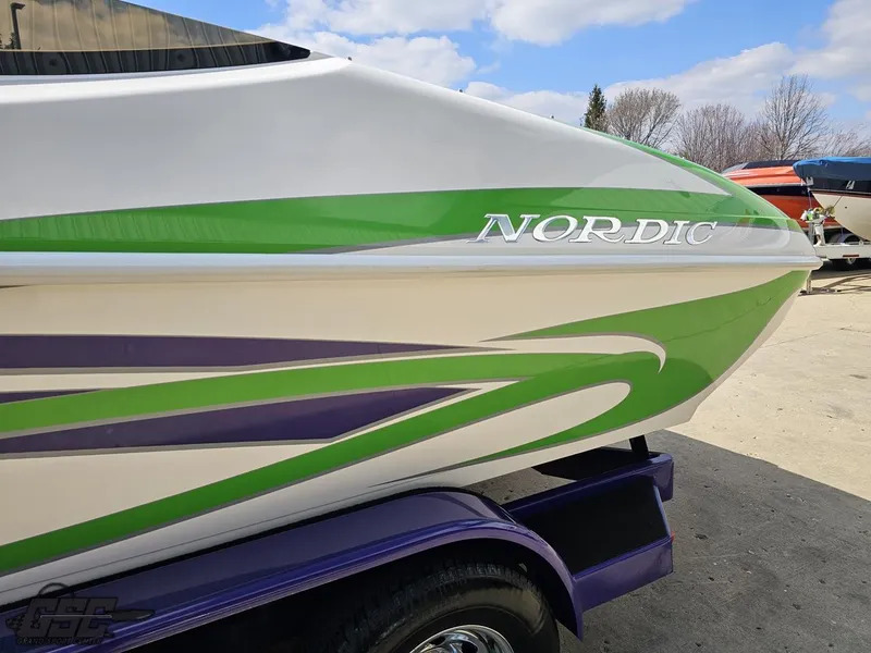 Slide: The Image of 2007 Nordic 28 Heat MCOB boat with green and purple accents on a trailer. - 27