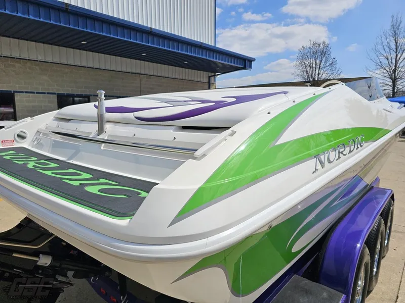 Slide: The Image of 2007 Nordic 28 Heat MCOB boat with green and purple accents on a trailer. - 36