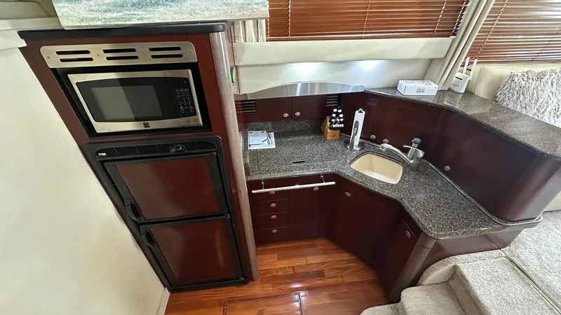 Slide: The Image of 2006 Sea Ray 44 Sedan Bridge kitchen with microwave, sink, and wooden cabinetry. - 11