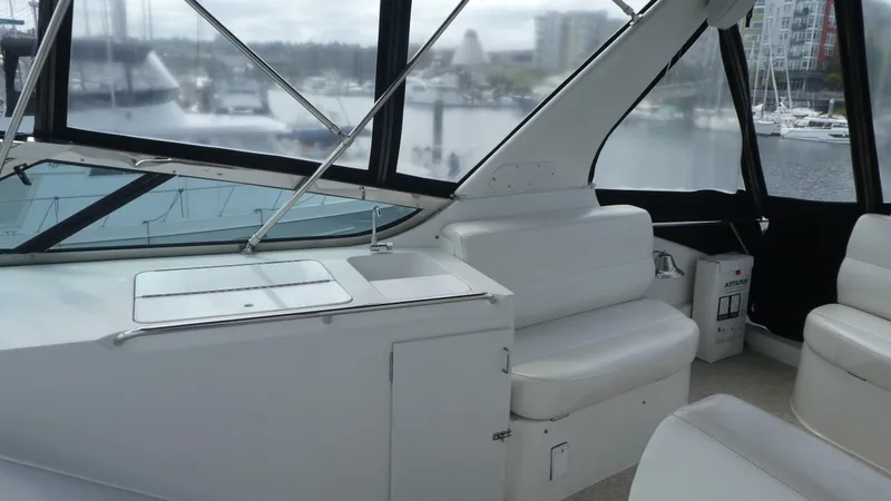 Slide: The Image of 1998 Carver 530 Voyager Pilothouse interior with white seating and marina view. - 48