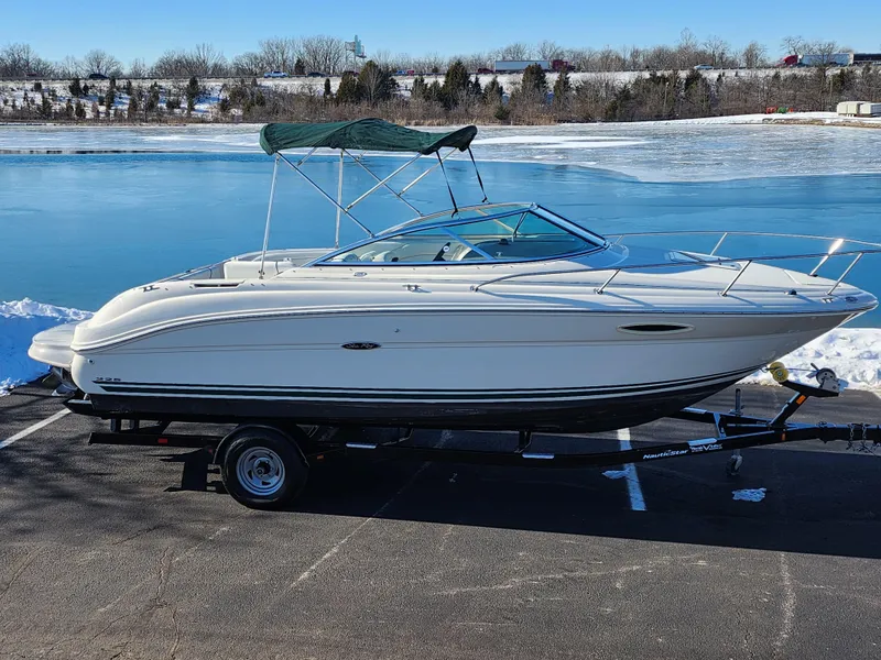 Slide: The Image of 2004 Sea Ray 225 Weekender boat on trailer by a frozen lake. - 0
