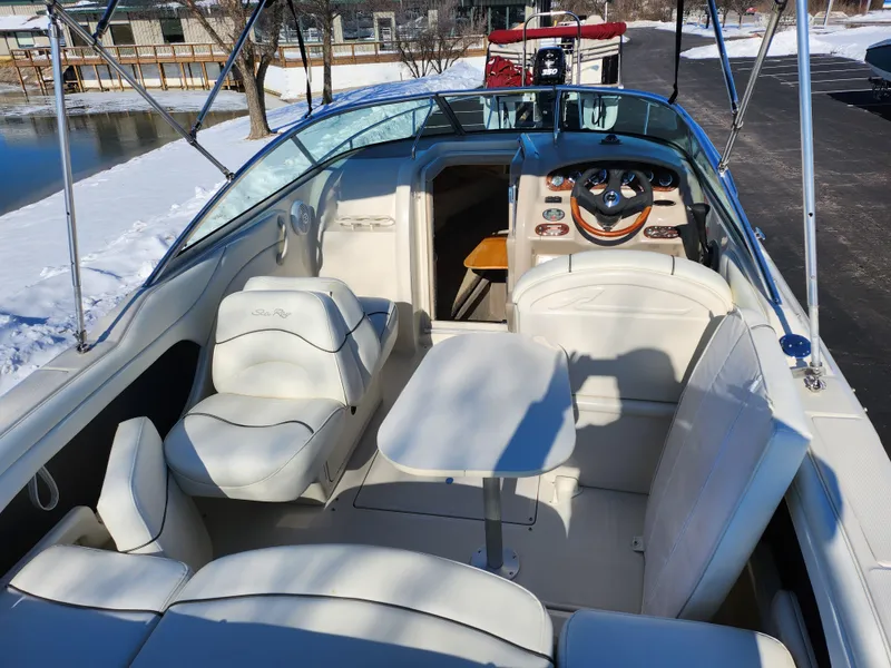 Slide: The Image of 2004 Sea Ray 225 Weekender boat interior with seating and table, docked in snowy setting. - 10
