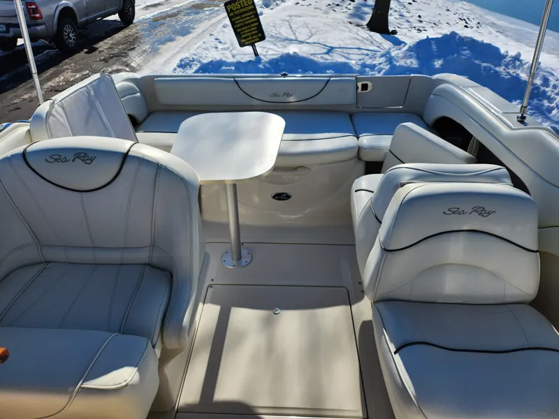 Slide: The Image of 2004 Sea Ray 225 Weekender boat interior with white seating and table, parked near snow. - 19
