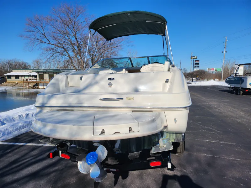 Slide: The Image of 2004 Sea Ray 225 Weekender boat with canopy, parked on a snowy lakeside road. - 2