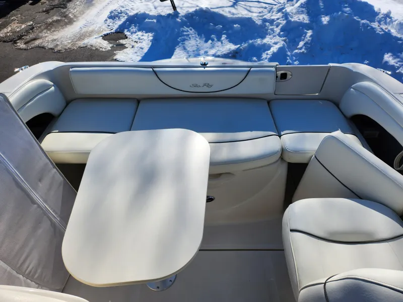 Slide: The Image of 2004 Sea Ray 225 Weekender boat interior with white seating and table, snow in background. - 20
