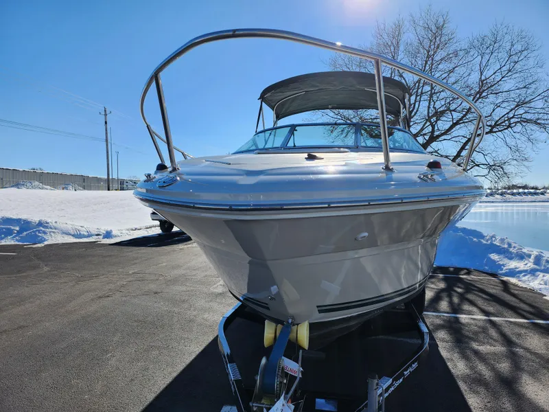 Slide: The Image of 2004 Sea Ray 225 Weekender boat on trailer, parked on snowy pavement under clear blue sky. - 6