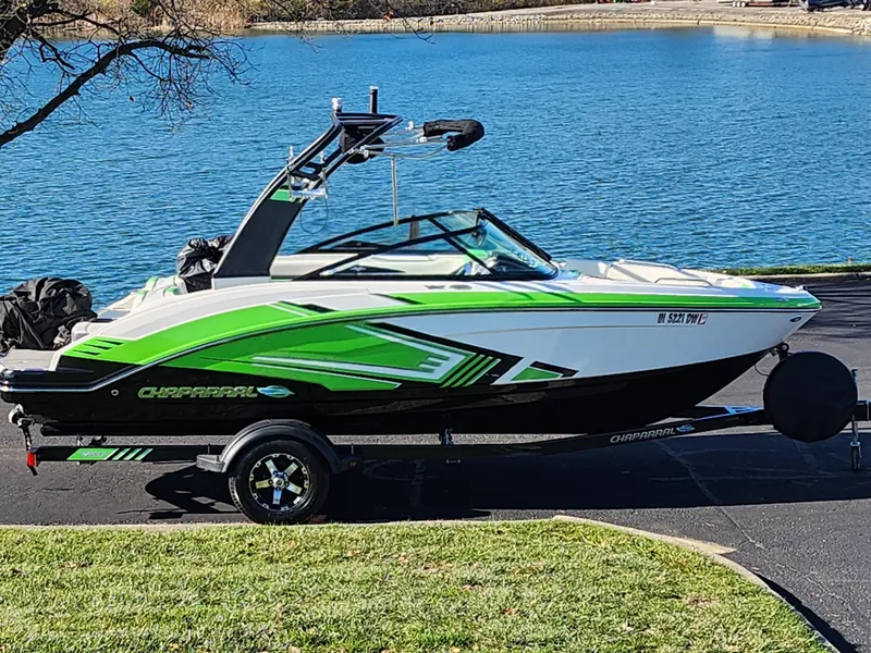 Slide: The Image of 2016 Chaparral Vortex 203 VRX boat with green accents on a trailer by a lake. - 0