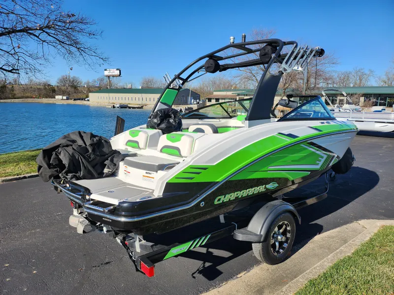 Slide: The Image of 2016 Chaparral Vortex 203 VRX boat with green accents parked near a lake. - 1