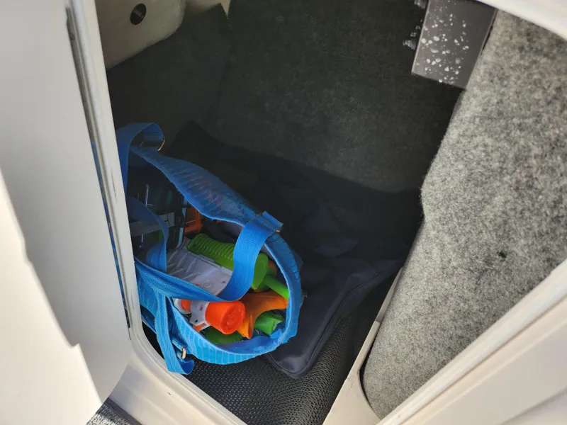 Slide: The Image of Storage compartment in 2016 Chaparral Vortex 203 VRX with blue bag and colorful items. - 16