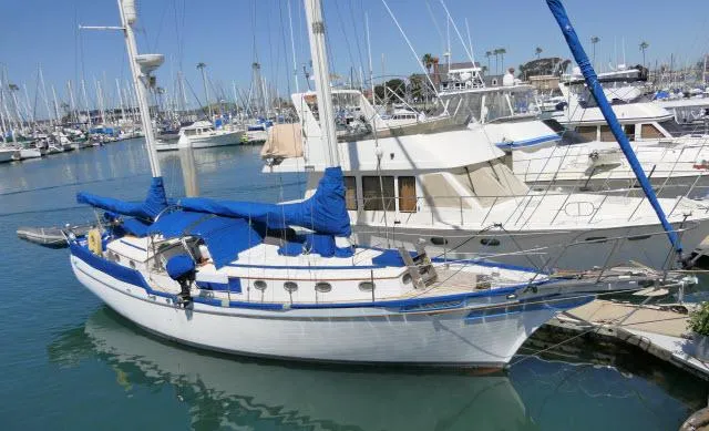 The Image of 1978 Brewer 45 Ketch sailboat docked in a marina, featuring blue covers and clear skies. - 1