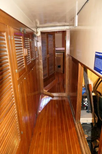 Slide: The Image of Wood-paneled hallway inside a 1978 Brewer 45 Ketch sailboat, featuring polished floors and storage cabinets. - 13