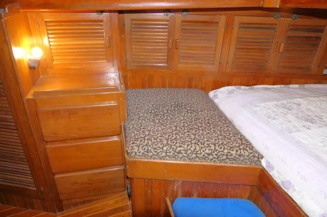 Slide: The Image of 1978 Brewer 45 Ketch cabin interior with wooden storage and patterned bedding. - 15