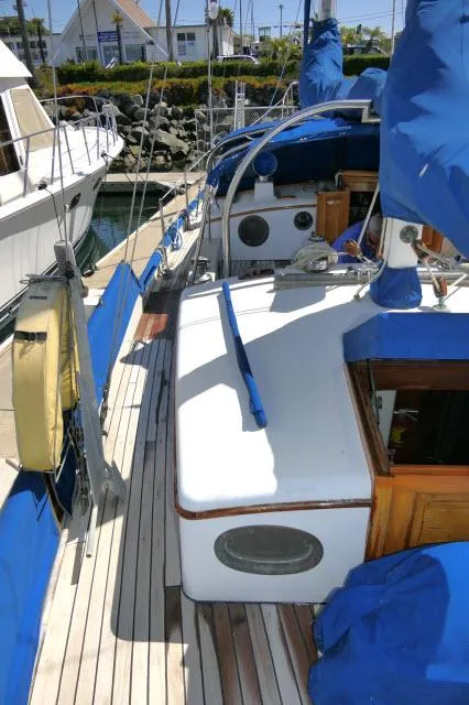 Slide: The Image of 1978 Brewer 45 Ketch sailboat docked, featuring blue covers and wooden accents. - 32