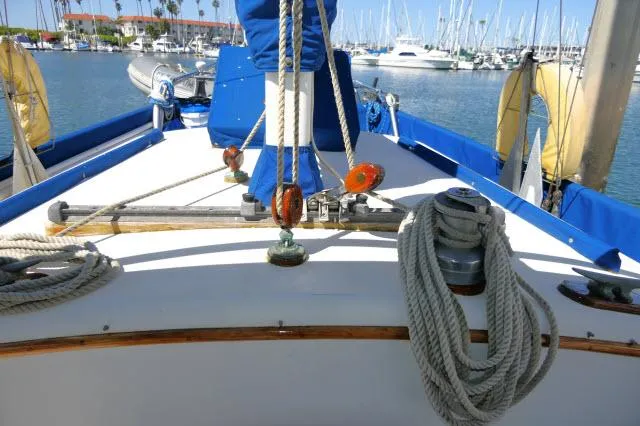 Slide: The Image of 1978 Brewer 45 Ketch sailboat deck with ropes and marina view. - 34
