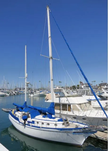 Slide: The Image of 1978 Brewer 45 Ketch sailboat docked in a marina under clear blue skies. - 42